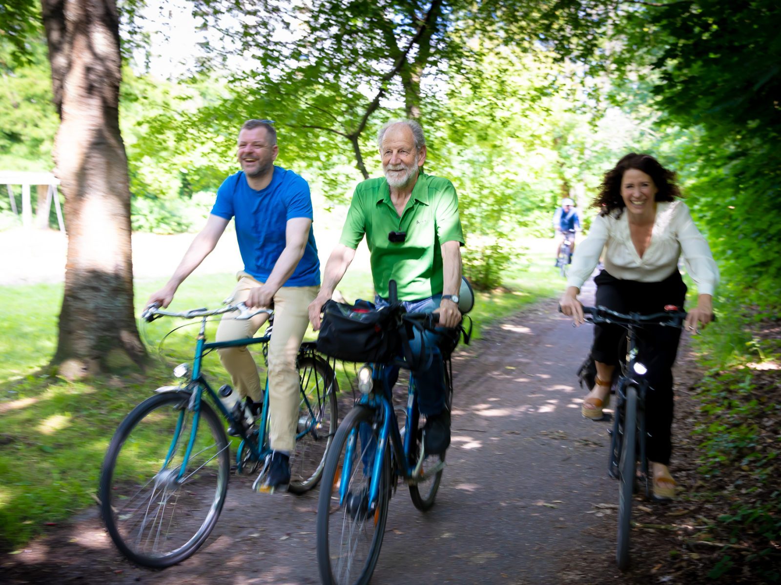 Das Bild zeigt drei Menschen. Sie fahren auf Fahrrädern durch einen Wald. Es handelt sich dabei von links nach rechts um den Fraktionsvorsitzenden Werner Graf, den ehemaligen Abgeordnteten Michael Cramer und die Fraktionsvorsitzende Bettina Jarasch.