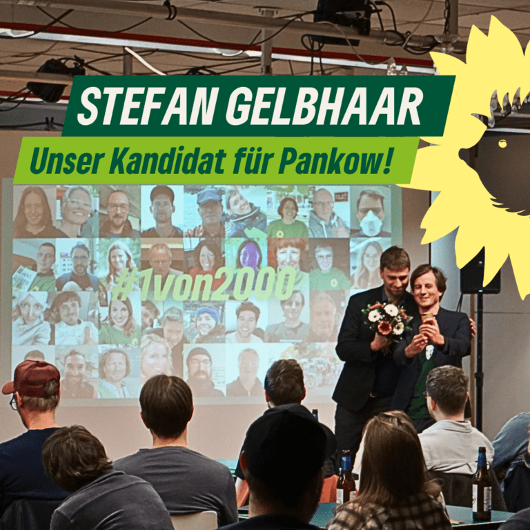 Das Bild zeigt die Nominierungsveranstaltung von Stefan Gelbhaar als Direktkandidat für Bündnis 90/Die Grünen im Wahlkreis Pankow. Im Vordergrund überreicht eine Person Stefan einen Blumenstrauß. Beide wirken erfreut und stolz. Im Hintergrund ist eine Leinwand zu sehen, auf der zahlreiche Selfies von Mitgliedern des Kreisverbands Pankow zu einer Collage zusammengestellt sind, zusammen mit dem Hashtag „#1von2000“. Oben im Bild steht in großen, grünen Lettern: „STEFAN GELBHAAR – Unser Kandidat für Pankow!“ Neben dem Text ist das grüne Sonnenblumen-Logo der Partei zu sehen. Vor der Leinwand sitzt das Publikum und verfolgt die Szene.