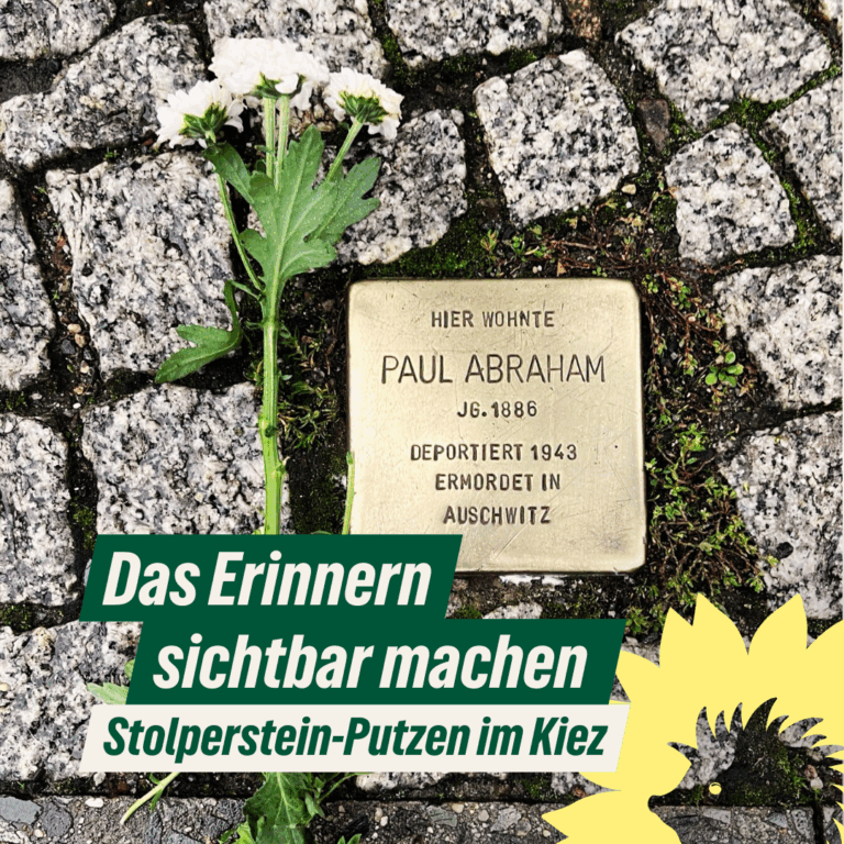 „Ein geputzter Stolperstein für Paul Abraham, umgeben von Kopfsteinpflaster. Daneben liegt eine weiße Chrysantheme als Zeichen des Gedenkens. Darüber ein grüner Textbalken mit der Aufschrift: ‚Das Erinnern sichtbar machen – Stolperstein-Putzen im Kiez‘, ergänzt um die Sonnenblume mit Igel-Silhouette von BÜNDNIS 90/DIE GRÜNEN Berlin.