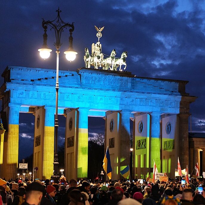 Kundgebung auf dem Pariser Platz in Berlin gegen den Einmarsch Russlands in die Ukraine vor dem mit der ukrainischen Flagge beleuchteten Brandenburger Tor.